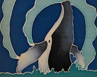 Puede incluir: Una pieza de arte textil que muestra una ballena azul oscuro emergiendo sobre un fondo azul profundo con acentos de agua en azul claro. La sección inferior es de color verde azulado sólido. Una etiqueta blanca dice WHALE 2 www.turtlehand.com.