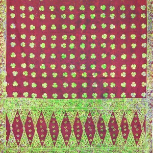 May include: A red fabric with a green floral pattern. The fabric has a green and white border with a geometric design.