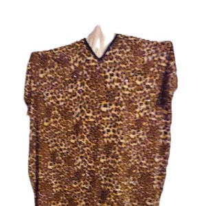 May include: A short-sleeved top with a V-neckline, featuring a brown and tan leopard print pattern. The top is hanging on a white hanger. The neckline is trimmed with a thin black border.