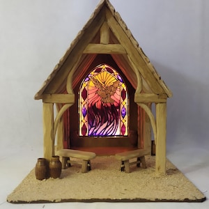 May include: A miniature wooden chapel with a stained-glass window depicting a dove. The chapel has a gabled roof, two benches, and two small barrels. The window is illuminated with warm colors.