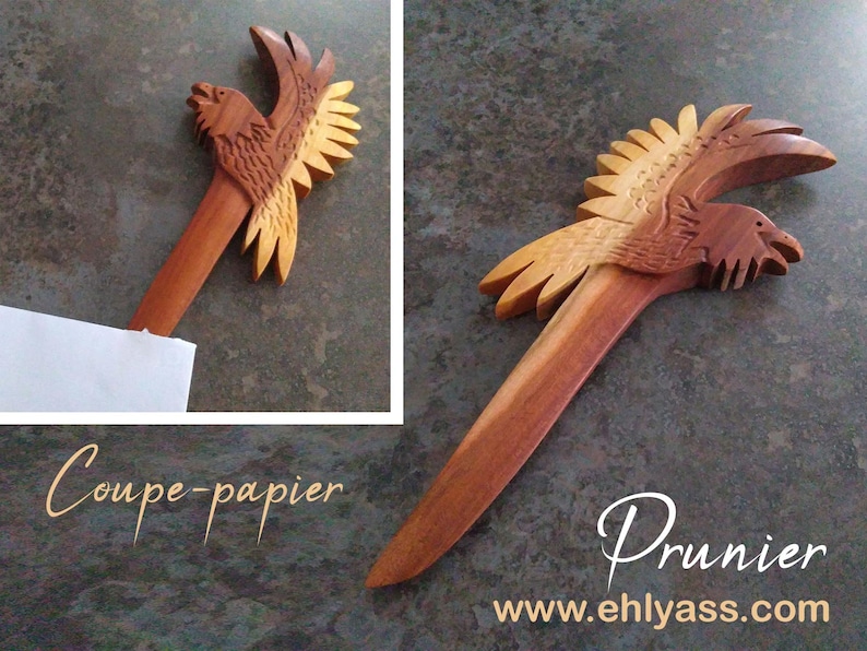May include: A wooden letter opener shaped like a bird with its wings spread. The bird is carved in a light brown wood with darker brown accents. The letter opener is about 12 inches long. The text "Coupe-papier" and "Prunier" are visible in the image.