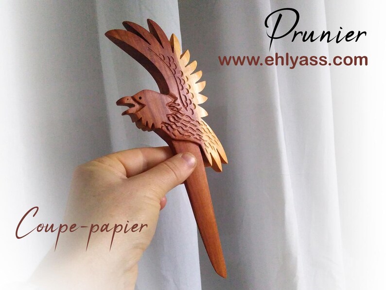 May include: A wooden letter opener shaped like a bird with wings spread. The bird is carved from wood with a reddish-brown color. The letter opener is about 10 inches long. The text "Coupe-papier" is visible in the image.