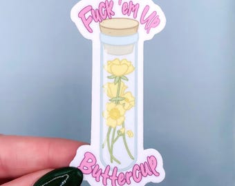 Könnte beinhalten: Ein Aufkleber mit einem durchsichtigen Fläschchen mit gelben Butterblumen im Inneren, das mit einem Korken verschlossen ist. Der Aufkleber hat einen rosa Text, der "Fuck 'em Up" und "Buttercup" lautet.