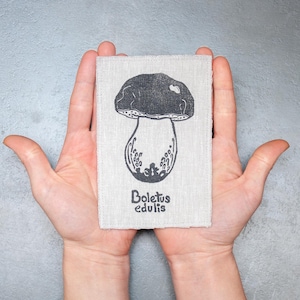 Może przedstawiać: Mały, prostokątny kawałek lnu z czarno-białym rysunkiem grzyba. Pod grzybem nadrukowany jest tekst "Boletus edulis".