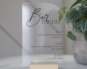 May include: Clear acrylic sign with rounded edges and a wooden base. The sign says "Bar Menu" in black script font and lists beer, wine, and spirits options.