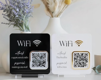 May include: Two square acrylic WiFi signs, one black and one white, each featuring a gold WiFi icon, printed network and password text, and a central QR code. The black sign displays network coppiceandcrafts and password makingculestuff, while the white sign shows network TheSmiths and password wifisonus.