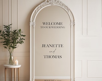 May include: White ornate mirror with a welcome sign that reads "Welcome to our wedding", the names "Jeanette and Thomas", and the date "August 9, 2025".