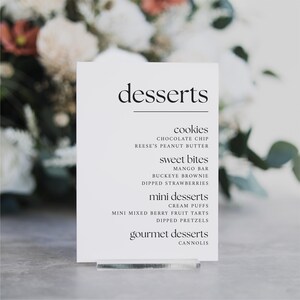 May include: A white sign with black text listing dessert options. The sign reads "desserts" at the top, followed by "cookies", "sweet bites", "mini desserts", and "gourmet desserts". Each category lists different dessert options.