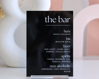 May include: Black sign with white text that reads "the bar" and lists drink options for a wedding or party. The options include "hers", "his", "beer", "spirits", and "non-alcoholic".
