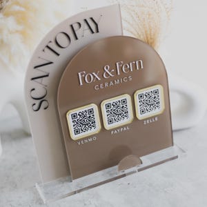 May include: A clear acrylic stand with a brown arched panel displaying "Fox & Fern Ceramics" and three QR codes for Venmo, PayPal, and Zelle. The words "SCAN TO PAY" are printed on a beige arched panel.
