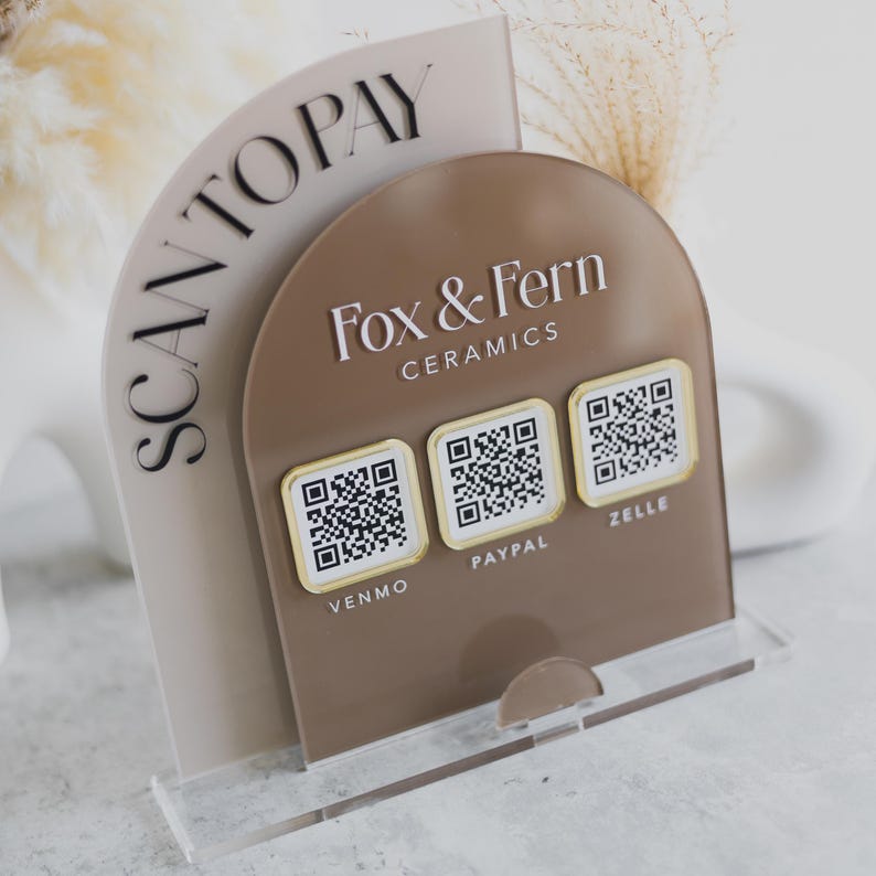 May include: A clear acrylic stand with a brown arched panel displaying "Fox & Fern Ceramics" and three QR codes for Venmo, PayPal, and Zelle. The words "SCAN TO PAY" are printed on a beige arched panel.