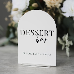 May include: White arch-shaped sign with black text that reads "Dessert bar" and "Please take a treat".