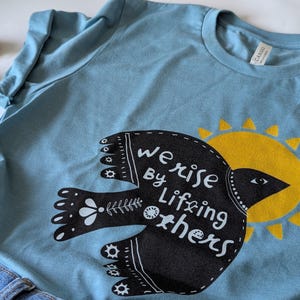 Inspirational Graphic Tee | We Rise by Lifting Others T-Shirt | Motivational T-Shirt | Gift for Friends | Uplifting Apparel | Social Justice