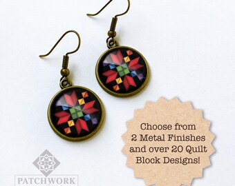 May include: A pair of round earrings with a bronze finish. Each earring features a colorful quilt block design on a black background. The earrings have a hook closure. The image also includes text that says "Choose from 2 Metal Finishes and over 20 Quilt Block Designs!"