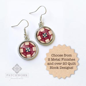 May include: Silver-toned earrings with a circular design featuring a geometric quilt block pattern in shades of red, cream, and blue. The earrings have a hook closure. The image also includes text that says "Choose from 2 Metal Finishes and over 20 Quilt Block Designs!"