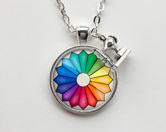 May include: A silver necklace with a round pendant featuring a colorful color wheel and a small silver sewing machine charm.