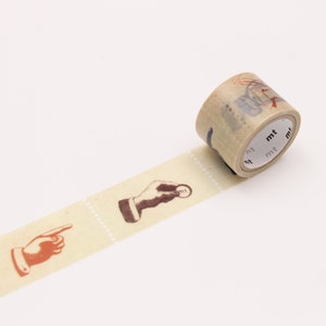 May include: A roll of beige washi tape with a repeating pattern of hands making different gestures. The tape is partially unrolled and the end of the roll shows the brand name "mt" printed on the tape.