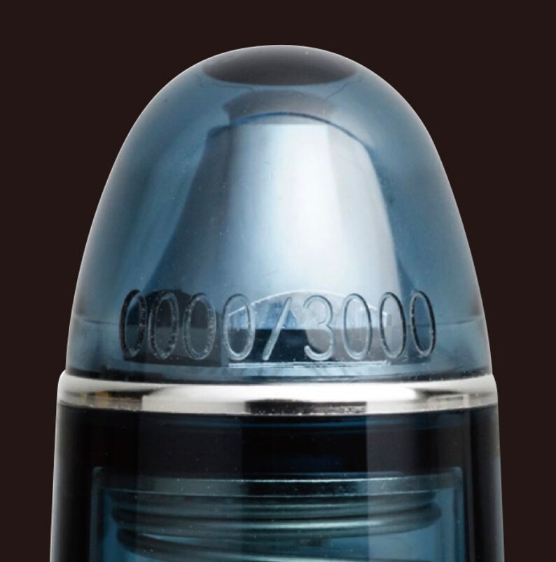 May include: Close-up of a blue pen cap with a silver band and the number "0000/3000" engraved on the cap.