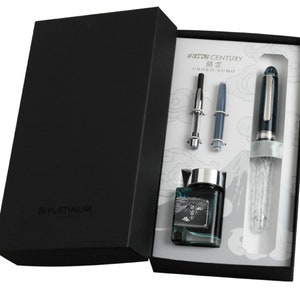 May include: A black box with a Platinum #3776 Century Urushi-Gumo fountain pen, a converter, a cartridge, and a bottle of ink. The pen has a clear, textured barrel and a silver trim. The ink bottle is clear with a green liquid and a mountain scene on the label.