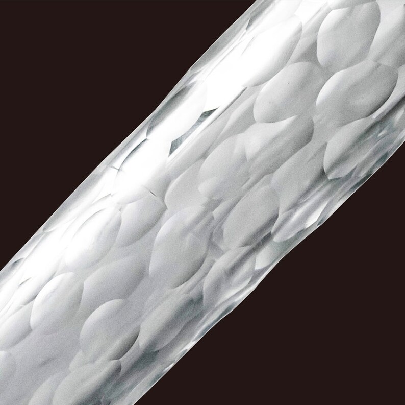 May include: Close-up of a clear glass rod with a textured surface. The surface is covered in small, raised bumps that create a pattern.