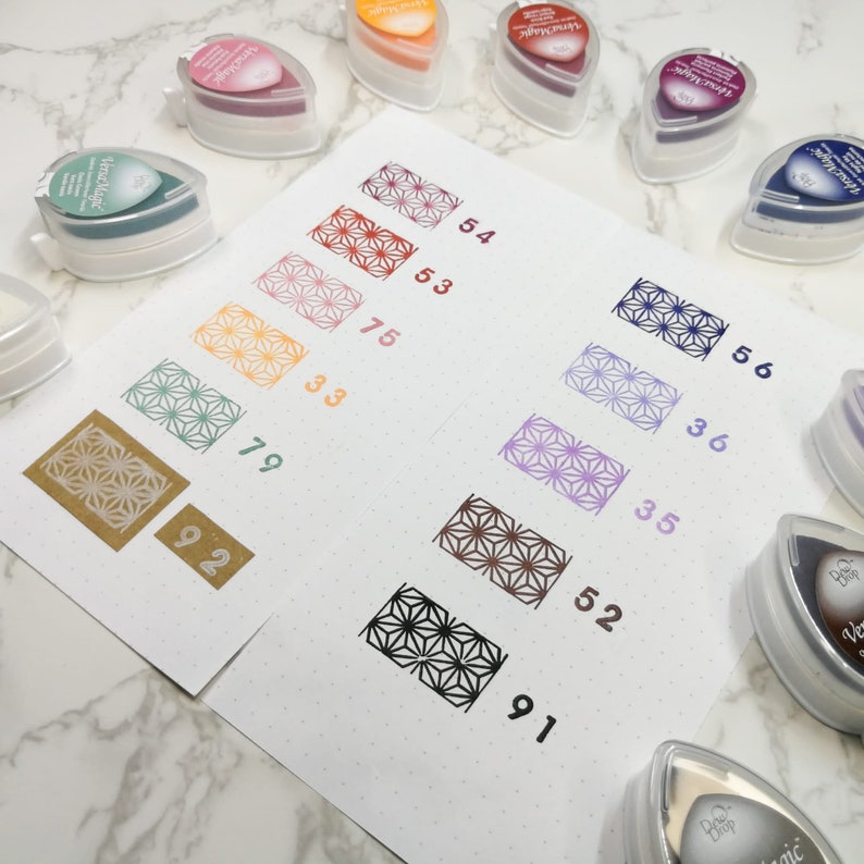 May include: A set of eight ink pads with different colors and a geometric pattern. The ink pads are arranged in a row from left to right, with the colors ranging from light to dark. The ink pads are labeled with numbers 56, 54, 36, 53, 75, 35, 33, 52, 79, 91, and 92.
