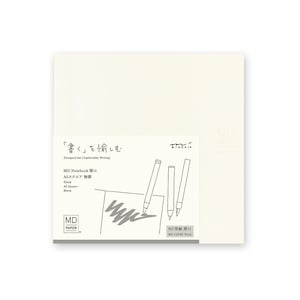 May include: A cream-colored MD Paper A5 square notebook with the text "Designed for Comfortable Writing" and Japanese text. The notebook has a thick paper and a blank interior. The cover features a drawing of pens and a sketch.