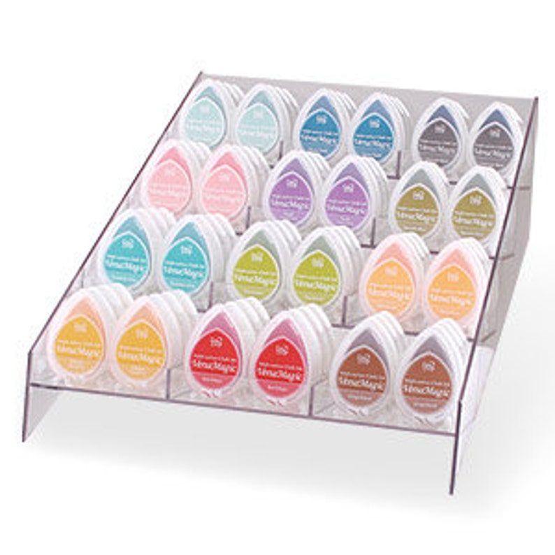 May include: A clear acrylic display stand with 36 teardrop-shaped ink pads in various colors. The ink pads are labeled "Tsukineko" and are arranged in rows on the stand.