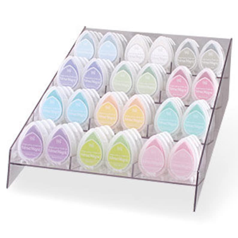 May include: A clear acrylic display stand with 36 ink pads in various pastel colors. The ink pads are arranged in rows and are shaped like teardrops.