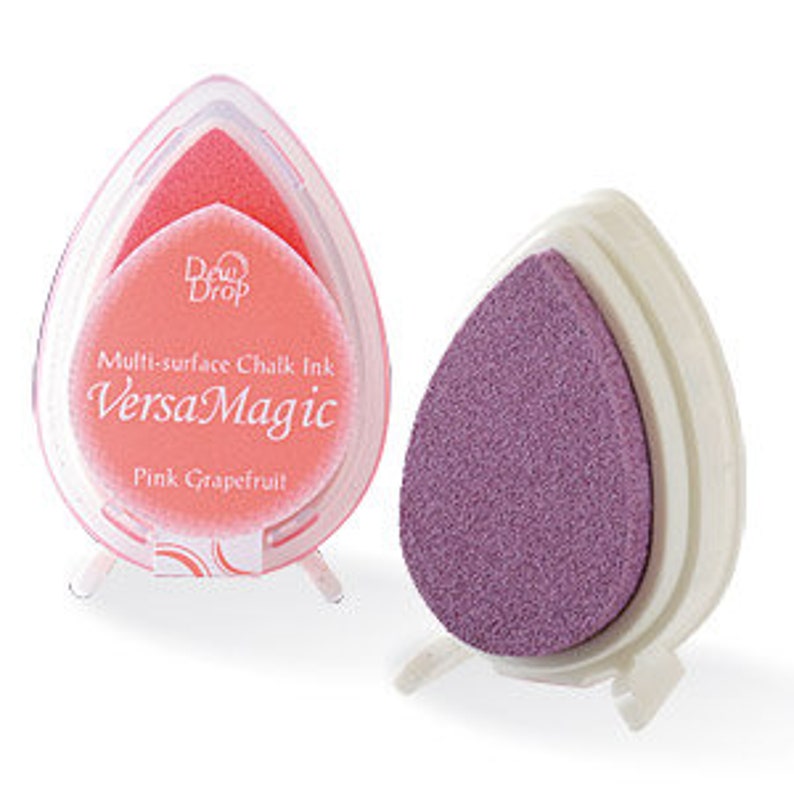 May include: Two pink and purple ink pads in a teardrop shape. The ink pads are labeled "Multi-surface Chalk Ink VersaMagic Pink Grapefruit!"