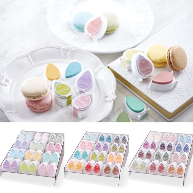 May include: A set of 36 colorful ink pads in a clear plastic display stand. The ink pads are shaped like teardrops and are arranged in rows of 12. The ink pads are in a variety of colors, including pink, blue, green, yellow, and purple.