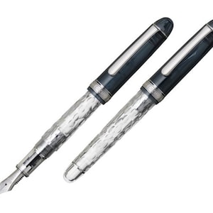May include: Two silver and blue fountain pens with a textured design. The pens have a clear barrel and a silver cap.