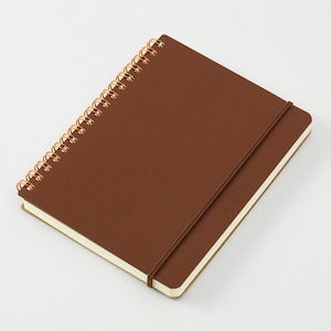 May include: A brown spiral-bound notebook with a matching elastic closure. The notebook has a textured cover and gold-colored spiral binding. The pages have cream-colored edges. The notebook is closed and angled slightly.