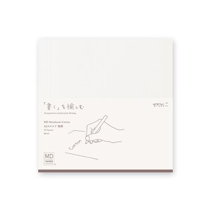 May include: A white MD Paper A5 notebook with a cream-colored cover. The cover features Japanese text, a pen drawing, and the word "Cotton." The notebook is designed for comfortable writing.
