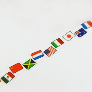 Puede incluir: Un fondo blanco con una fila de banderas coloridas que representan diferentes países. Las banderas están dispuestas en diagonal desde la esquina superior derecha hasta la esquina inferior izquierda. Las banderas incluyen Estados Unidos, Japón, Australia, Francia, Países Bajos, Jamaica, México y China.