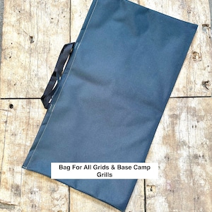 May include: A dark blue canvas bag with black handles and the text "Bag For All Grids & Base Camp Grills" printed on the front.