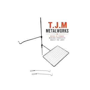 May include: A black metal cooking system featuring a vertical pole, a horizontal arm with a hook, a rectangular wire grill grate, and two separate metal handles. The text T.J.M METALWORKS OVER 10 YEARS MAKING PRODUCTS BUILT TO LAST is visible.