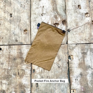 May include: A brown canvas pouch with a zipper closure and a small Union Jack flag patch. The pouch is labeled "Pocket Fire Anchor Bag".