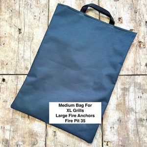 May include: A black canvas bag with a handle. The bag is labeled "Medium Bag For XL Grills Large Fire Anchors Fire Pit 35".