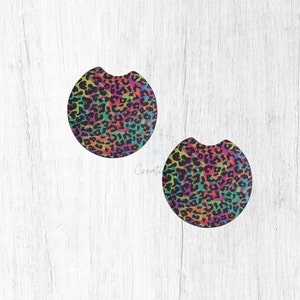 May include: Two round, black coasters with a rainbow leopard print design.