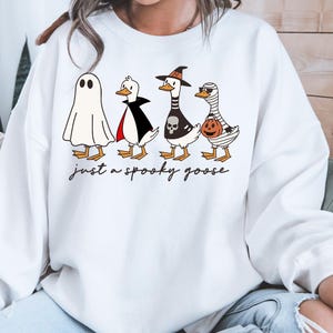 a woman wearing a white sweatshirt with three cartoon characters on it