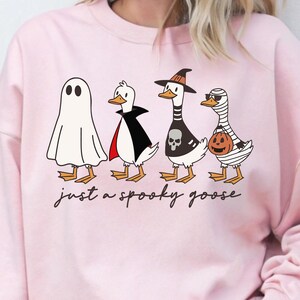 a woman wearing a pink sweatshirt with three cartoon characters on it