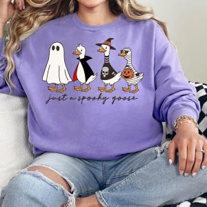 a woman sitting on a couch wearing a purple sweater with three penguins on it