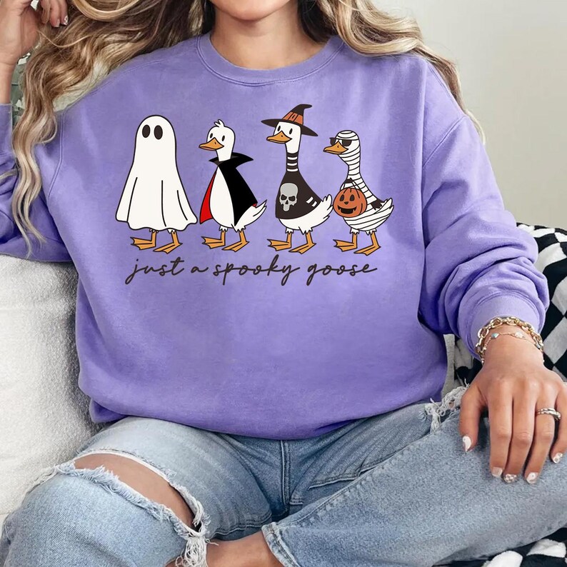 a woman sitting on a couch wearing a purple sweater with three penguins on it