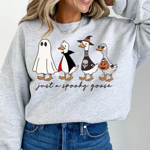 a woman wearing a grey sweatshirt with three cartoon characters on it