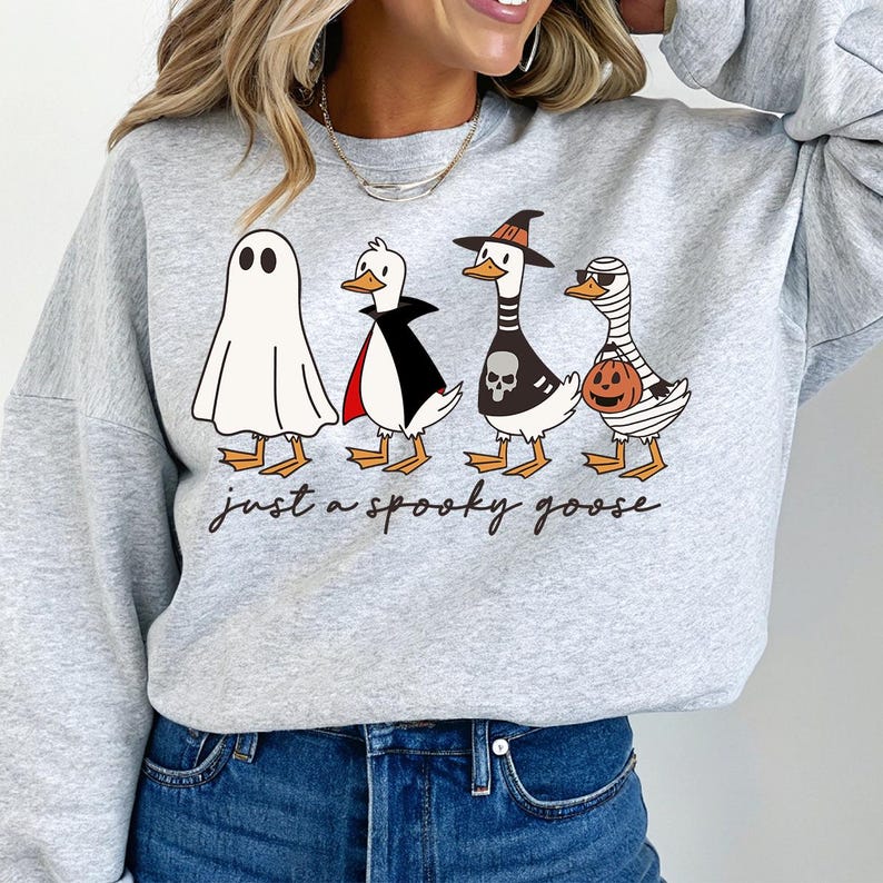 a woman wearing a grey sweatshirt with three cartoon characters on it