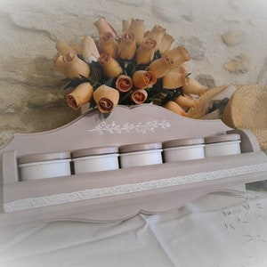 Peut inclure: Un porte-épices en bois gris clair avec une bordure en dentelle blanche et six pots en céramique blanche. Le porte-épices est décoré d'un motif floral et est monté sur une surface blanche.