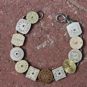 May include: A bracelet made from vintage watch faces. The bracelet is made of silver metal and has a variety of watch faces in different colors and styles. The watch faces are all round and have black numbers on a white background.