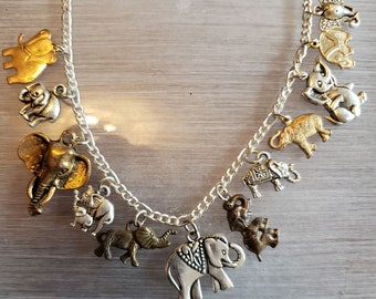 May include: A silver charm bracelet with multiple elephant charms, some gold and some silver. The charms are detailed and have different poses.
