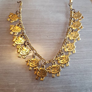 Könnte beinhalten: Ein goldenes Kettenarmband mit mehreren Schaf-Anhängern. Die Anhänger sind detailliert und haben eine strukturierte Oberfläche.