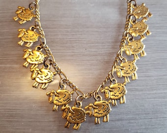 May include: A gold chain bracelet with multiple charms of sheep. The charms are detailed and have a textured finish.